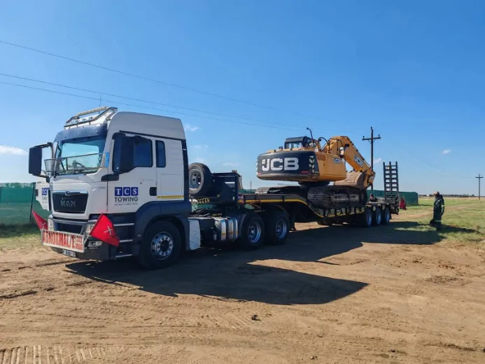 Heavy-duty truck transporting JCB excavator