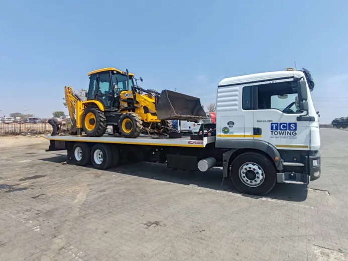 Heavy-duty truck hauling JCB backhoe loader